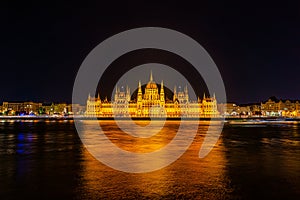 Illuminated historical building of Hungarian Parliament at night on Danube River Embankment.