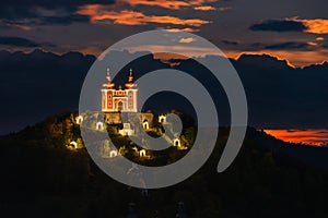 Illuminated historical monument. View of a church on top of a hill under a dramatic sky.