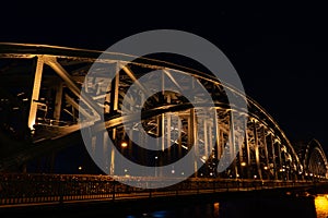 Illuminated Hohenzollern Arch Bridge details in Cologne, Germany at night