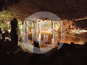 Illuminated lake inside of a dripstone cave.