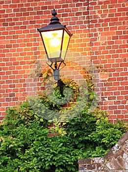 Illuminated lantern against brick wall
