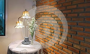 Illuminated lighting of The old vintage table lamp with daisies bouquet in glass vase on round table in retro restaurant