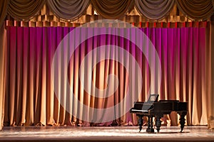 Illuminated by lights stage with backstage and decorative columns, there is an old grand piano