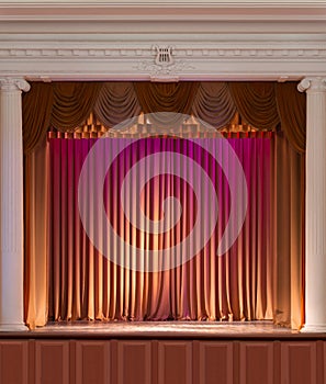 Illuminated by lights stage with backstage and decorative columns, there is an old grand piano