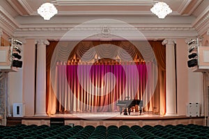 Illuminated by lights stage with backstage and decorative columns, there is an old grand piano