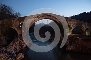 Illuminated medieval roman hump-backed stone arch bridge over Sella river in Cangas de Onis Oriente Asturias Spain