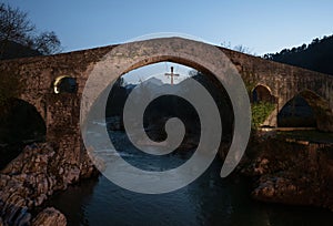 Illuminated medieval roman hump-backed stone arch bridge over Sella river in Cangas de Onis Oriente Asturias Spain