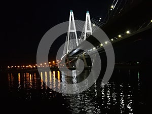 Illuminated modern cable-stayed bridge over the river in the night city