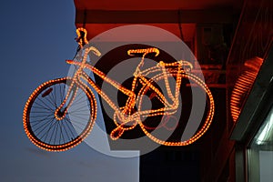 Illuminated old bicycle above the entrance of bicycle store and repair shop