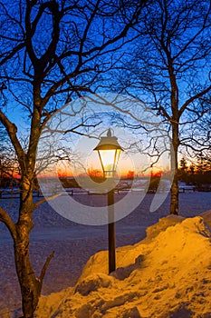 Illuminated old street lamp in winter landscape