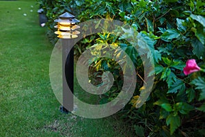 Illuminated outdoor light in apartment garden at twilight, evening.