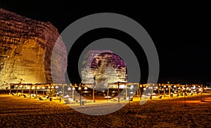 Illuminated outdoor lounge in front of elephant rock erosion monolith standing in the night desert, Al Ula, Saudi Arabia photo