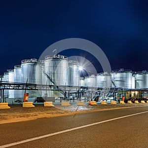 Illuminated petrochemical production plant against a blue sky at twilight, Antwerp