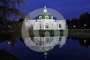 Illuminated picturesque Grotto Pavilion and its water reflection in swamped pond in Kuskovo manor park in autumn Moscow tonight
