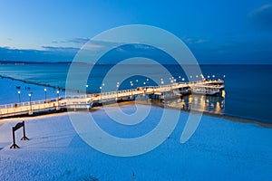 Illuminated pier in Brzezno on the winter beach at dusk, Gdansk.  Poland