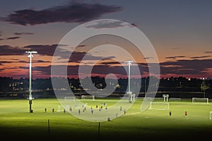 Illuminated public sports arena in North Port, Florida with people playing soccer game on grass football stadium at