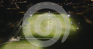 Illuminated public sports arena in North Port, Florida with people playing soccer game on grass football stadium at