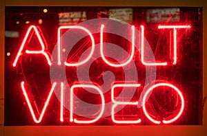 Illuminated red neon adult video sign on display