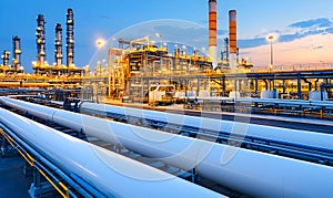 Illuminated refinery pipelines and complex structures at twilight