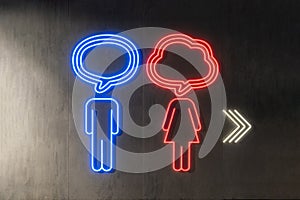 Illuminated Restroom Neon Sign With Arrow Symbols On dark wall background