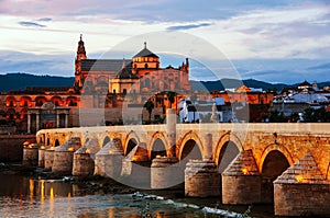 Illuminated Roman bridge and La Mezquita at sunset in Cordoba, Spain