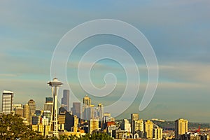 Illuminated Seattle skyscrapers and contour of Mount Rainier at sunset.