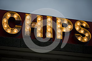 Illuminated sign at seaside fish and chip shop after dark