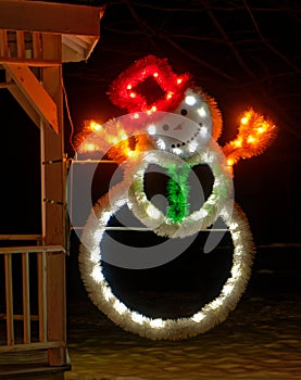 Illuminated snowman with hat at nighttime gazebo