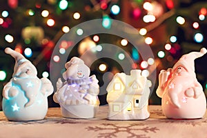 Illuminated Snowman and Jack Frost (Santa Claus) dolls in front of Christmas tree lights, blurred background