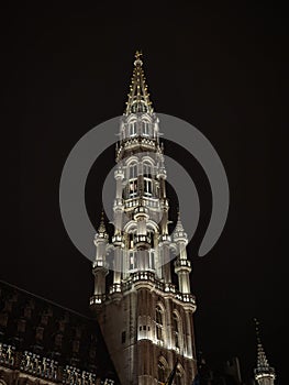 Illuminated spire tower of medieval gothic Brussels City Town Hall grand place grote markt square in night sky Belgium
