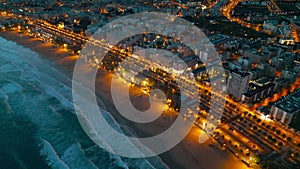 illuminated streets of Spanish touristic city Salou, Catalonia, aerial view of beach, sea and coast with palm trees