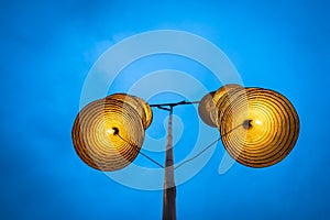 Illuminated stripe Vietnamese traditional conical hats hanging on wire for decoration, with blue sky at twilight