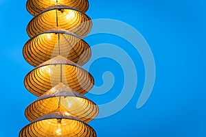 Illuminated stripe Vietnamese traditional conical hats hanging on wire for decoration, with blue sky at twilight