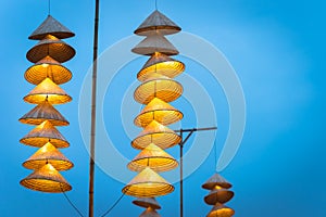 Illuminated stripe Vietnamese traditional conical hats hanging on wire for decoration, with blue sky at twilight