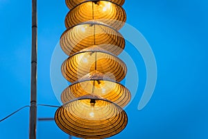Illuminated stripe Vietnamese traditional conical hats hanging on wire for decoration, with blue sky at twilight