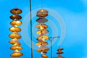 Illuminated stripe Vietnamese traditional conical hats hanging on wire for decoration, with blue sky at twilight