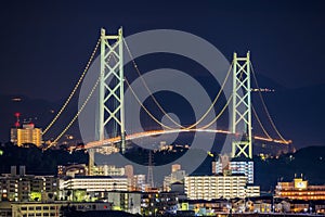 Illuminated Suspension Bridge Towers Over Apartment Buildings at Night