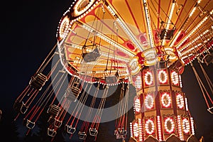 Illuminated swing chain carousel in amusement park at the night