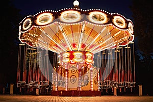 Illuminated swing chain carousel in amusement park at the night