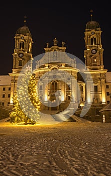 Illuminated swiss abbey of Einsiedeln in snowy Christmas time and winter night