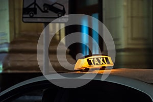 Illuminated taxi sign on the roof of a taxi at night city