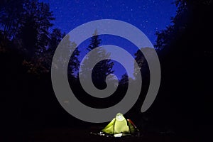 Illuminated tent at night in the forest