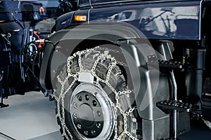 Illuminated wheel in the focus. Jeep with snow chains parked indoors at the white tile on vehicle show