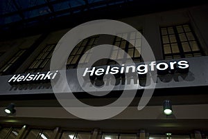 Illuminated white Sign on dark with the letters of Helsinki and Helsingfors, Finland photo