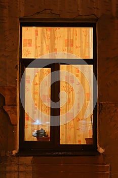 Illuminated window with curtained yellow curtains