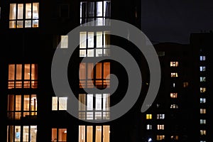 Illuminated windows of night multistory apartment building. Lighted night windows of house. City life background