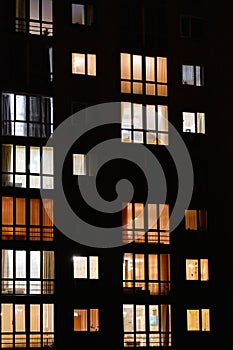 Illuminated windows of night multistory apartment building. Lighted night windows of house. City life background