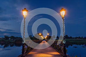 Illuminated wooden bridge over lake after sunset