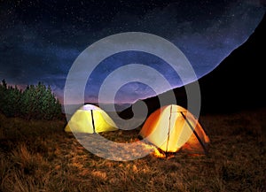 Illuminated yellow camping tent under stars