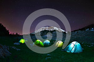 Illuminated yellow camping tent under stars at night